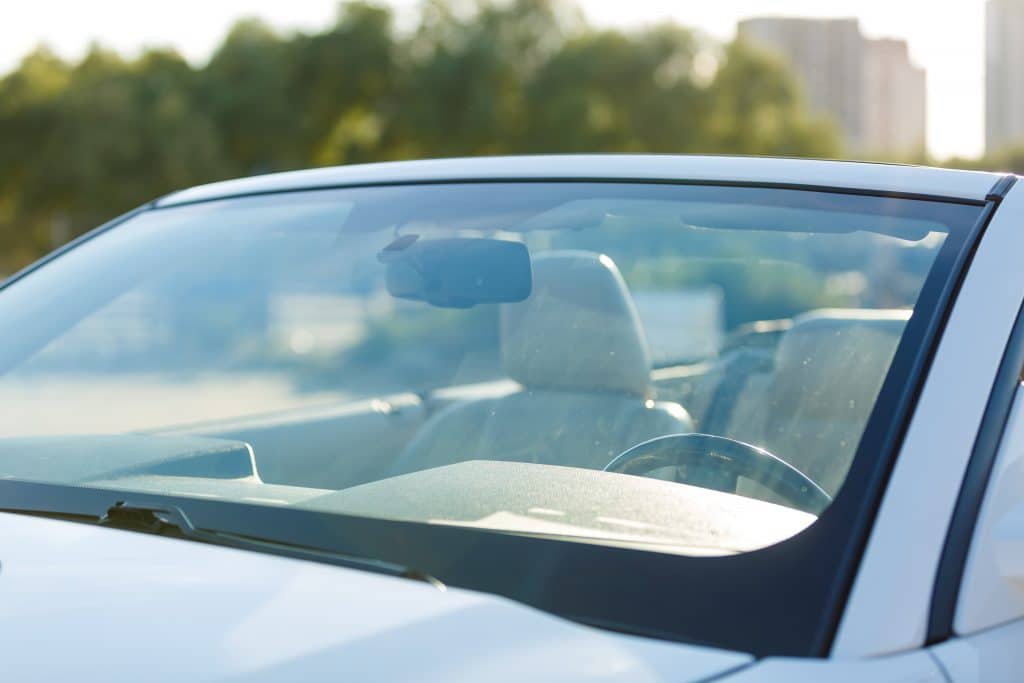 A white car with the driver's side window open, displaying a logo.