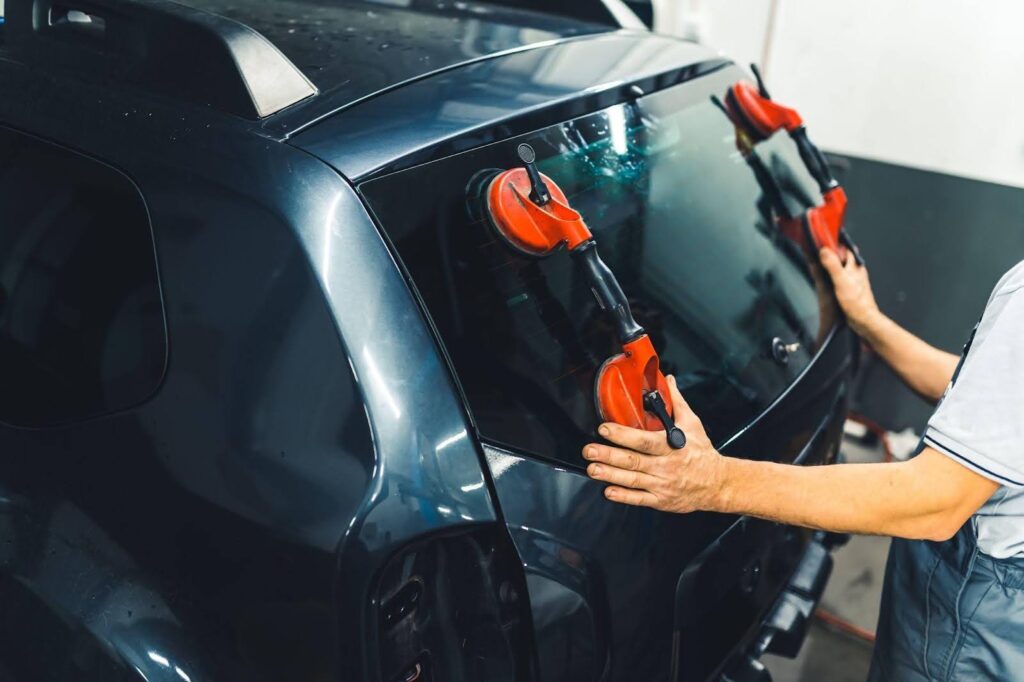 A man repairs a car, focusing on the window wiper, demonstrating automotive maintenance skills