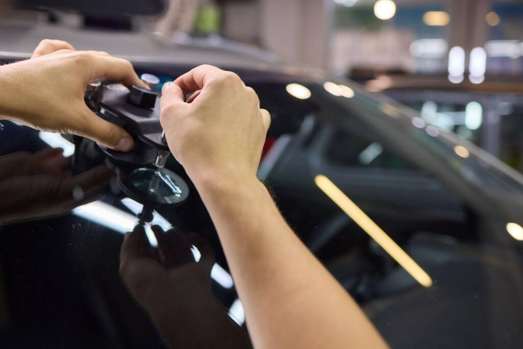 A person carefully uses a tool to remove a window, demonstrating precision and focus in their task