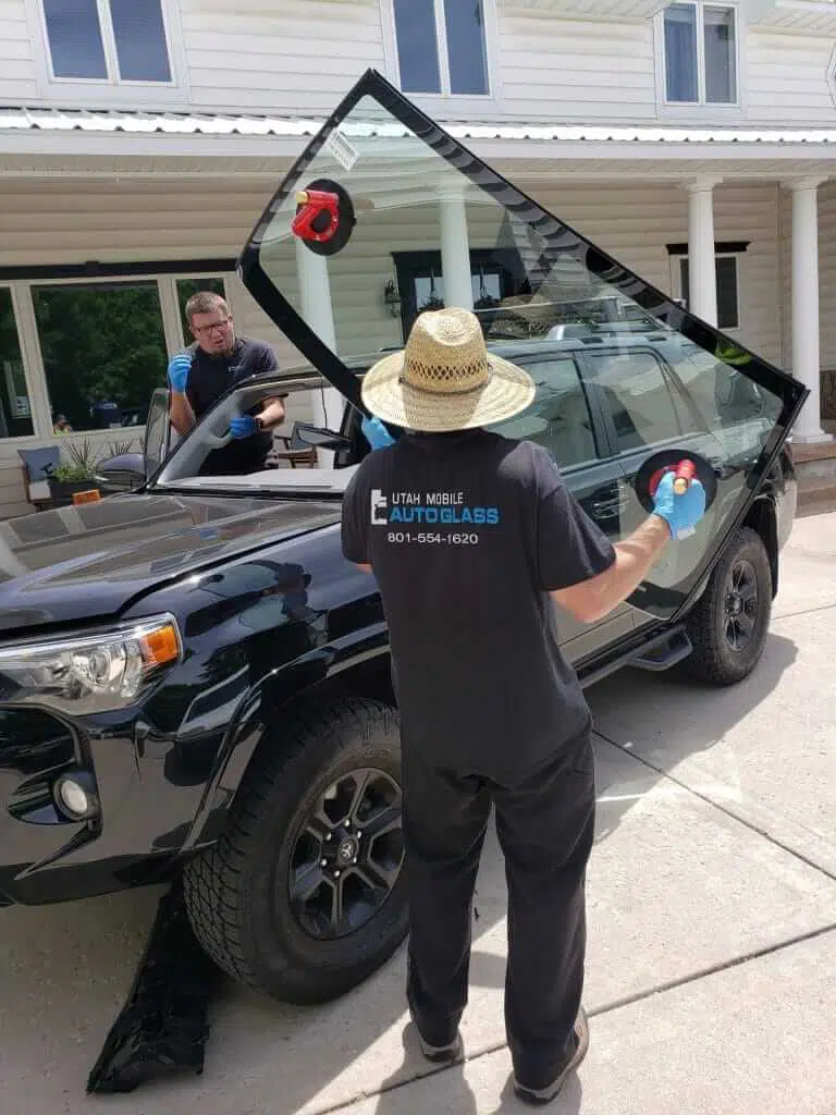 A man cleaning the windshield of a black SUV parked on a street.