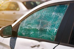 A damaged car with a shattered window and cracked windshield, showing its deterioration