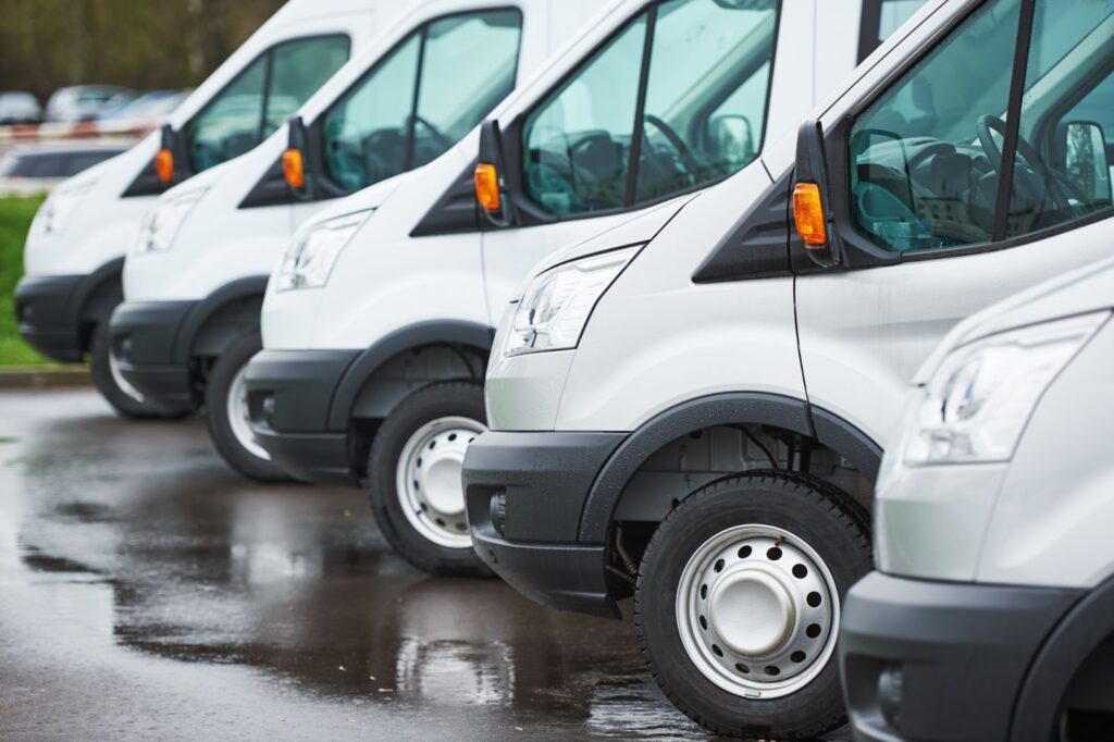 A line of white vans parked in a lot, offering fleet vehicle windshield repair and services