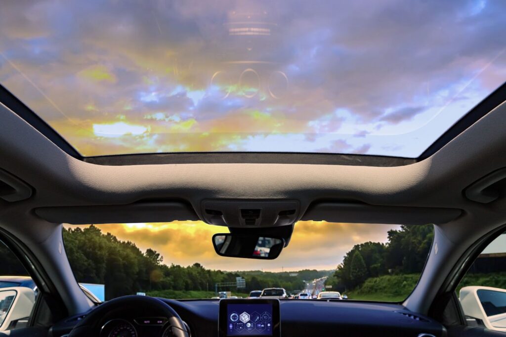 A sunset view from inside a car with a sunroof.