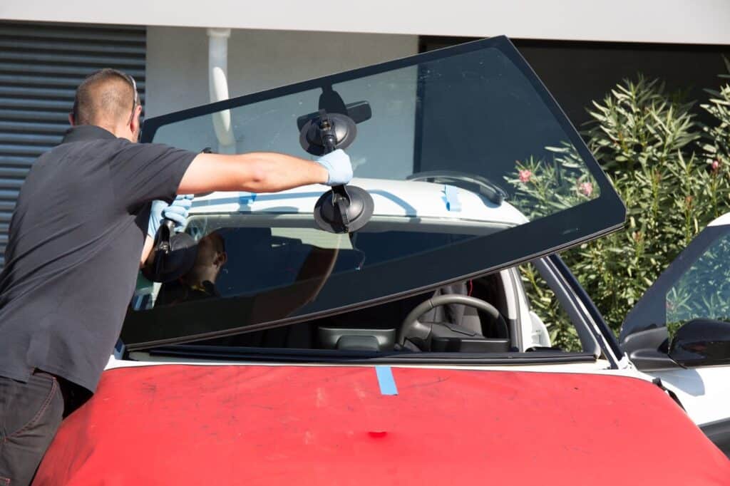 A man installing a new windshield on a car, focusing on windshield repair.