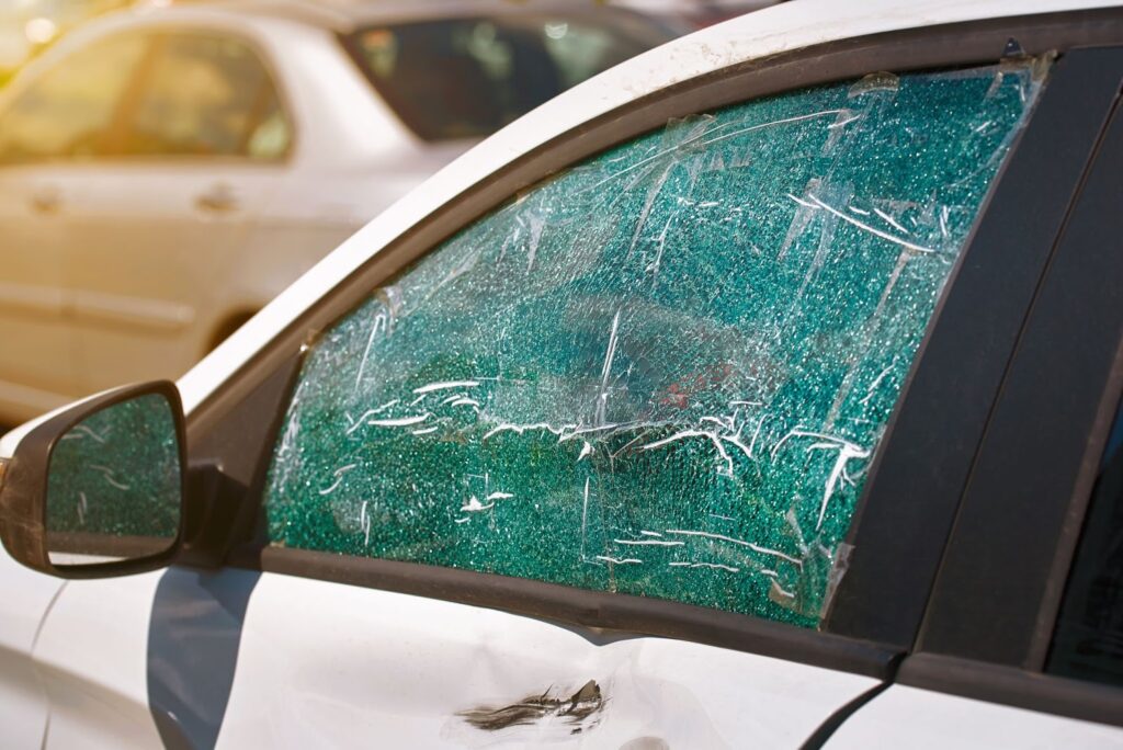 A car with a shattered window and cracked windshield, highlighting the need for immediate repair services nearby.