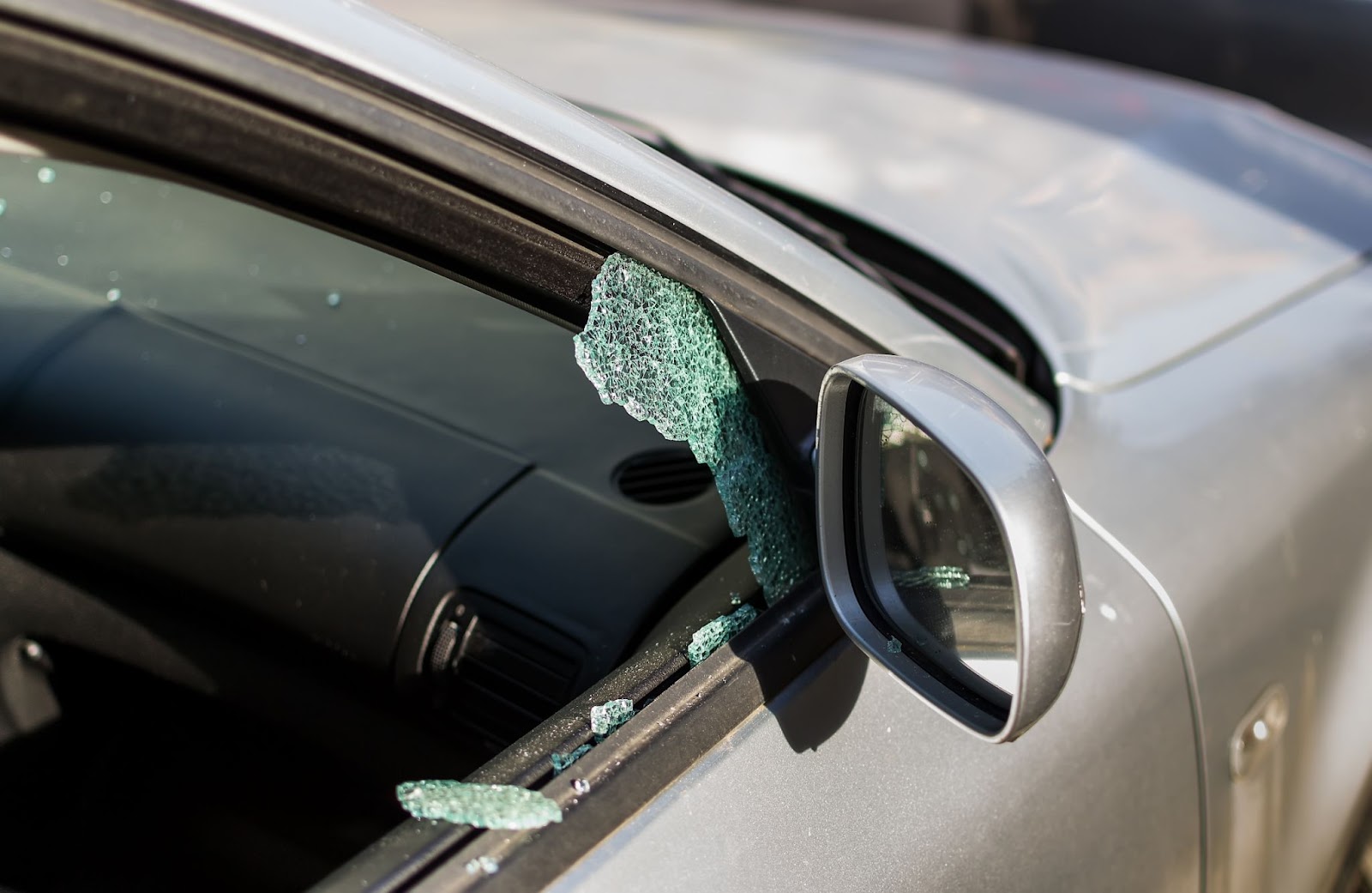 An automobile displaying a fractured window and a broken side mirror, indicating the necessity for nearby car window repairs.