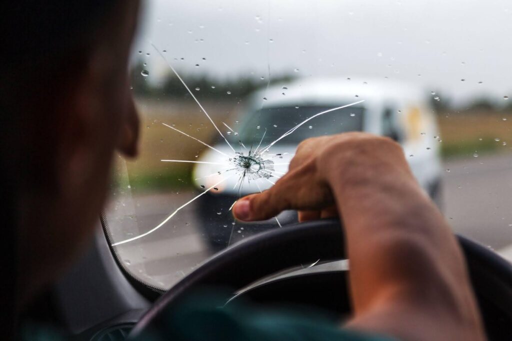 A driver with a shattered windshield, focused on the road 