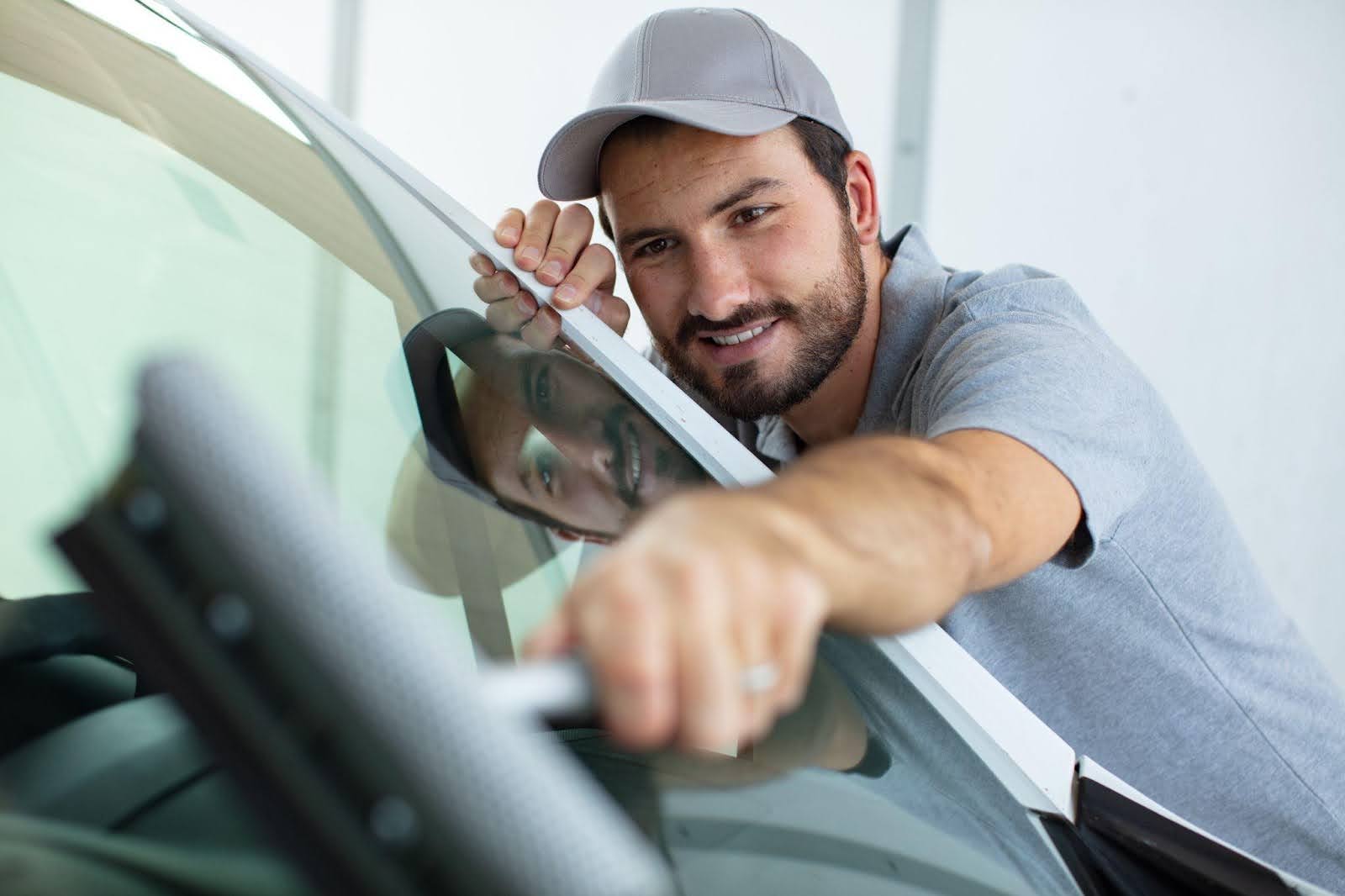 A man diligently cleans the windshield of his car, ensuring clear visibility for safe driving 