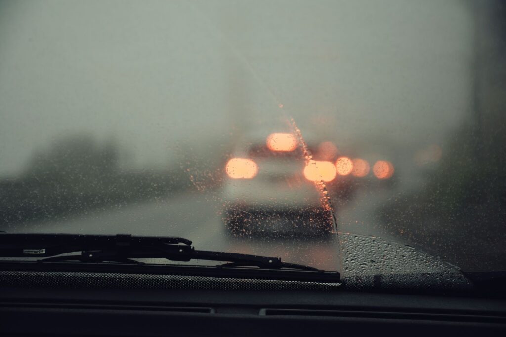 A car navigates a rainy road, highlighting the importance of mobile rock chip and windshield repair services.