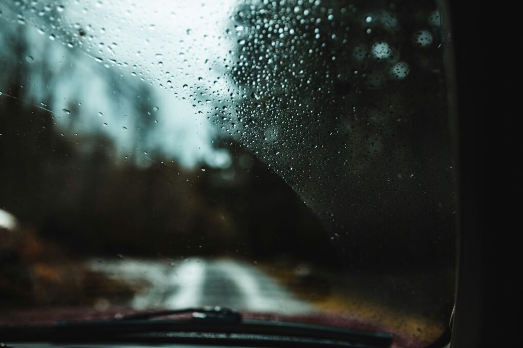 A car's windshield on a rainy day, highlighting the need for mobile rock chip and windshield repair services.