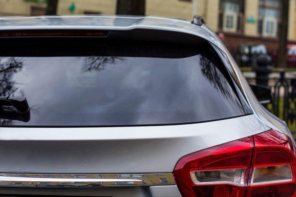 Rear view of a silver car parked on the street, highlighting its modern features against a city backdrop