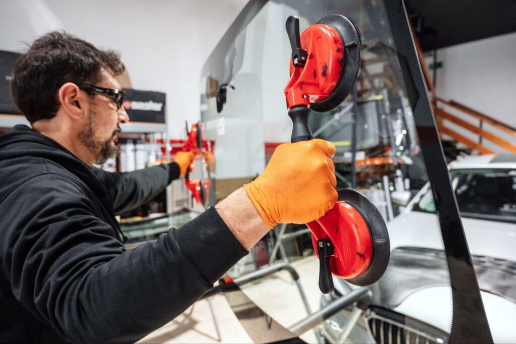 A man in a black shirt and gloves skillfully uses a glass cutter, demonstrating his expertise