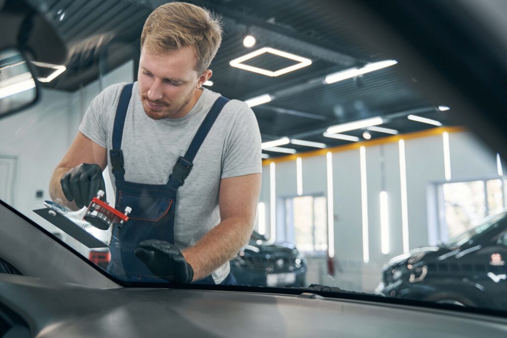 Auto glass technician performing windshield repair service