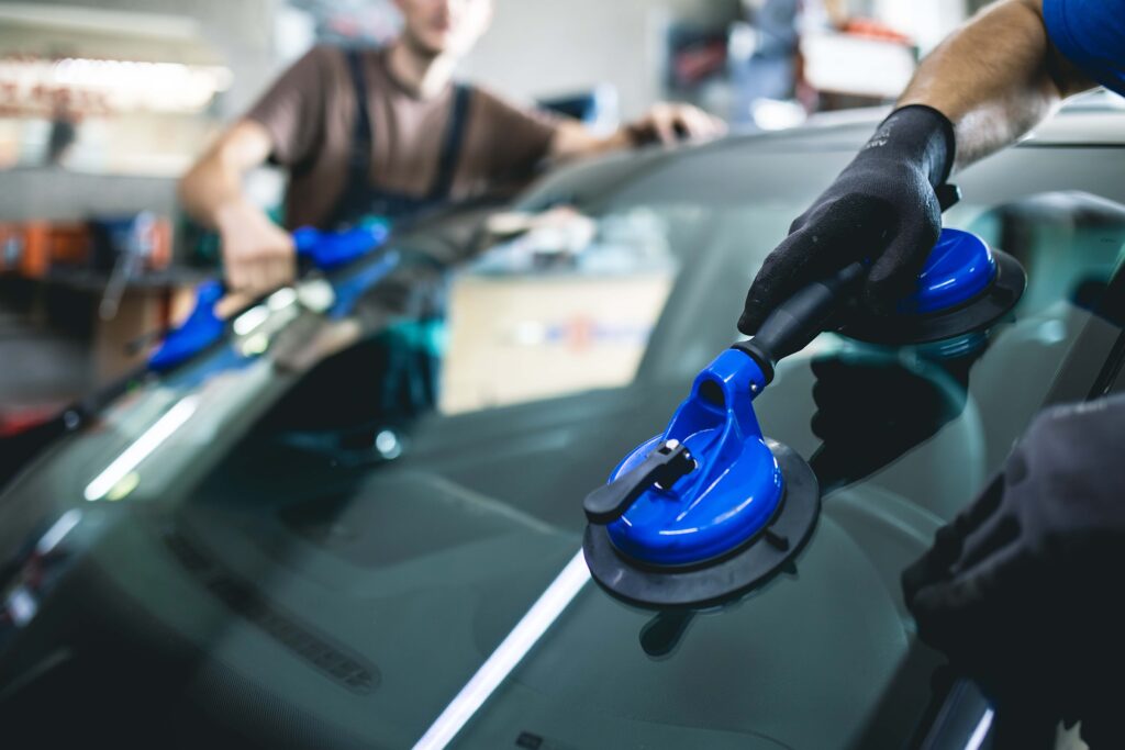 Mobile auto glass technician replacing windshield on vehicle