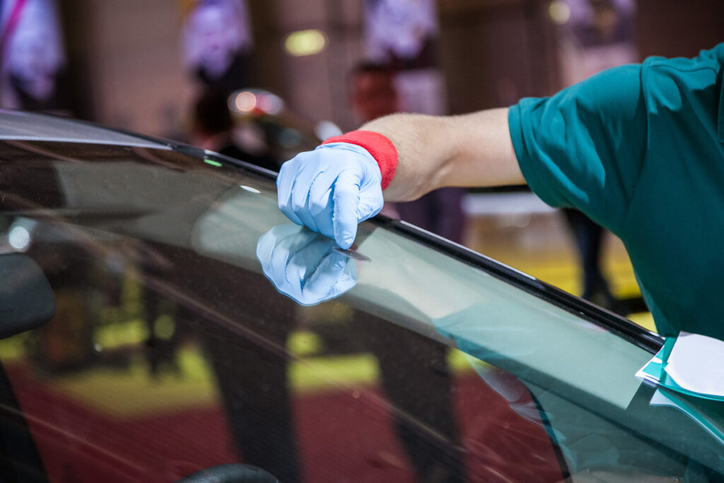 Auto glass technician inspecting windshield damage for repair